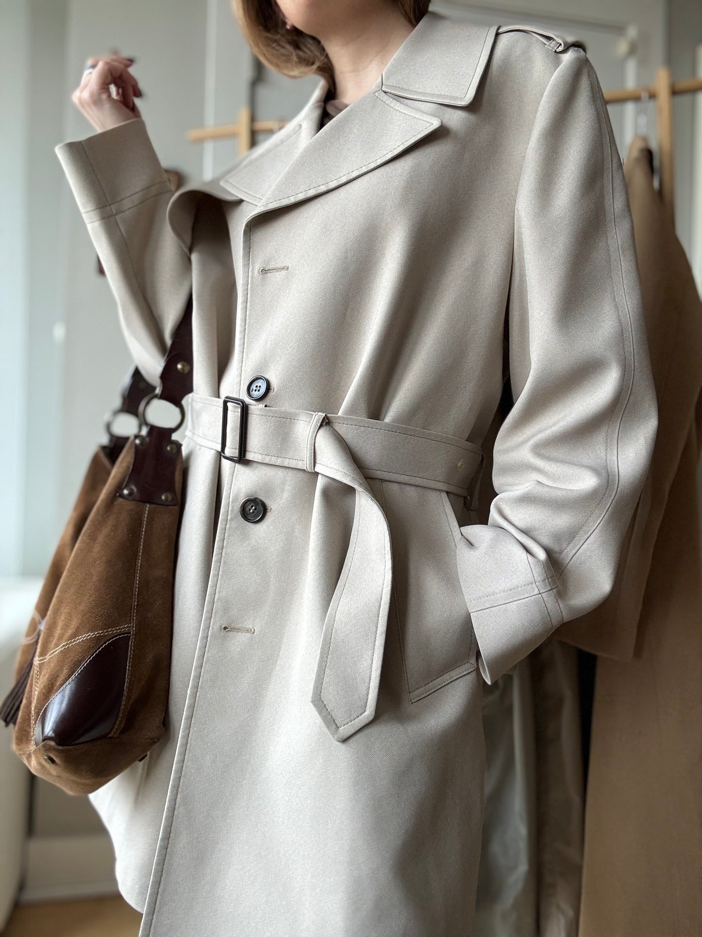 Woman wears a chic Vintage London Fog Trench coat paired with a brown suede bag.