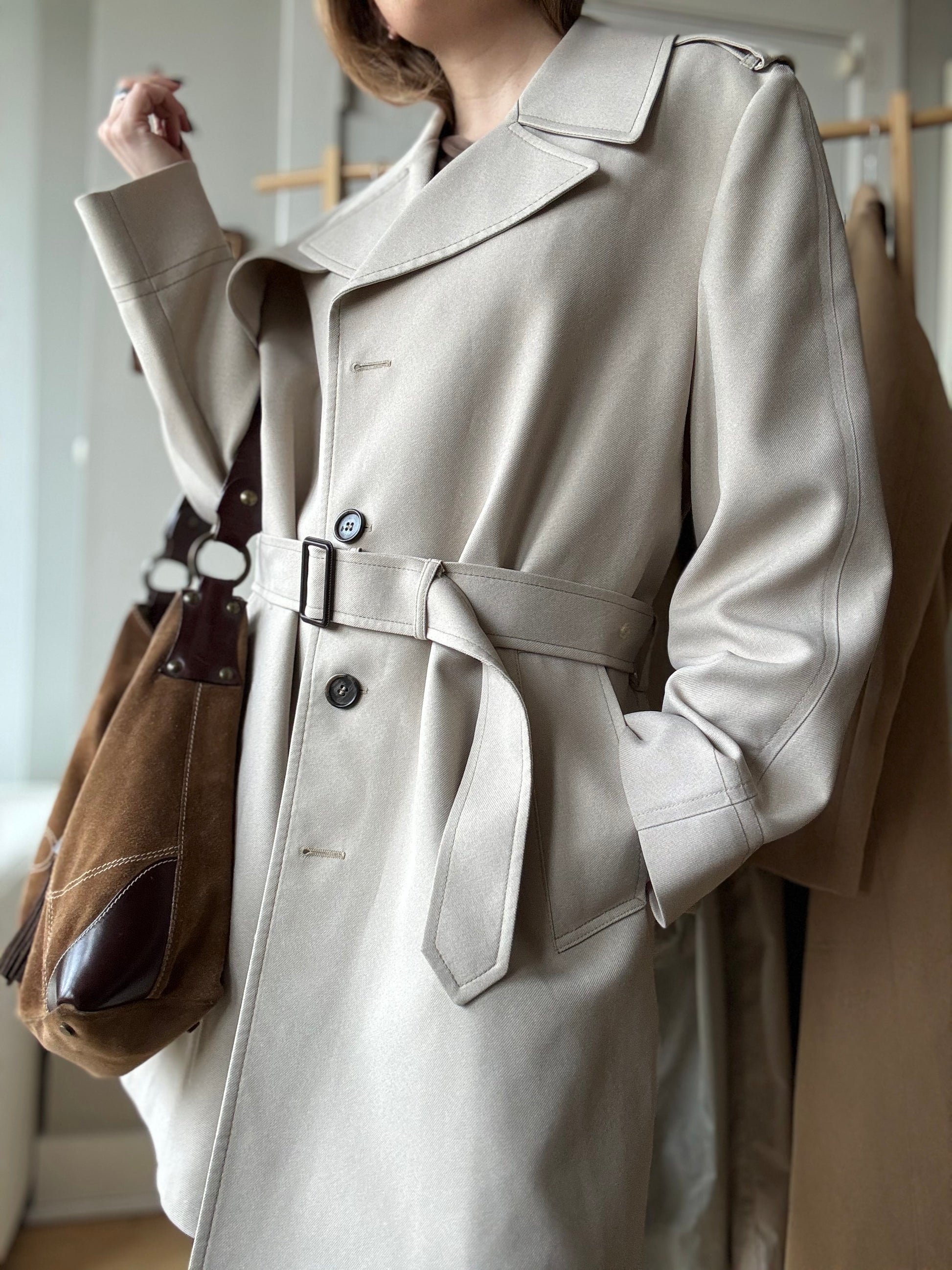 Woman wears a chic Vintage London Fog Trench coat paired with a brown suede bag.