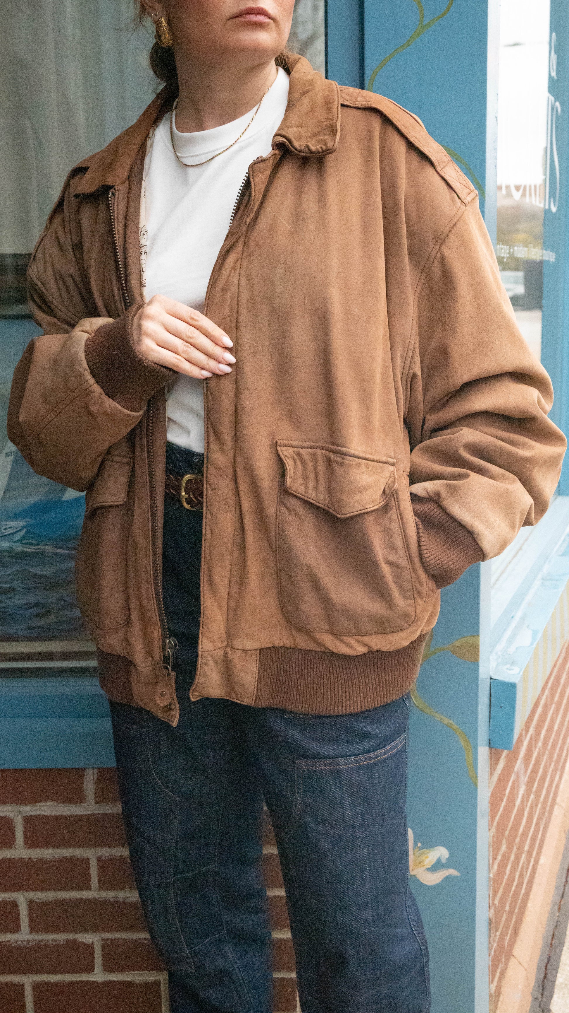 Woman poses in an oversized vintage brown leather jacket in front of boutique in West Town Chicago.