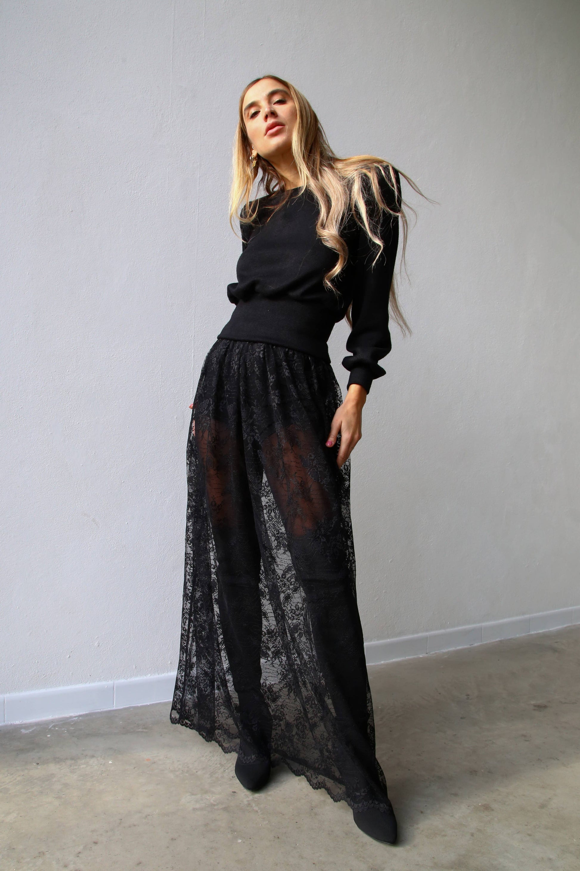 Woman wears a black sheer skirt paired with a black sweater and black tights for a chic statement outfit from Chicago Sustainable boutique in West Town.