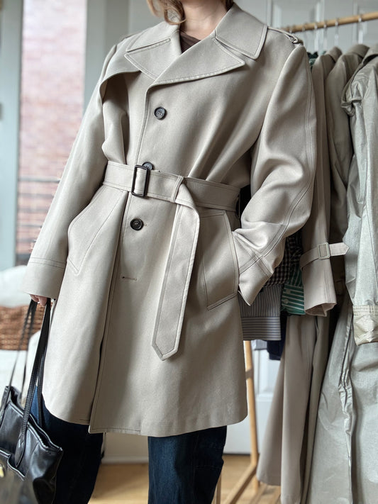 Woman wears spring Vintage London Fog Military trench coat styled with jeans and a black slouch bag for a chic city look.