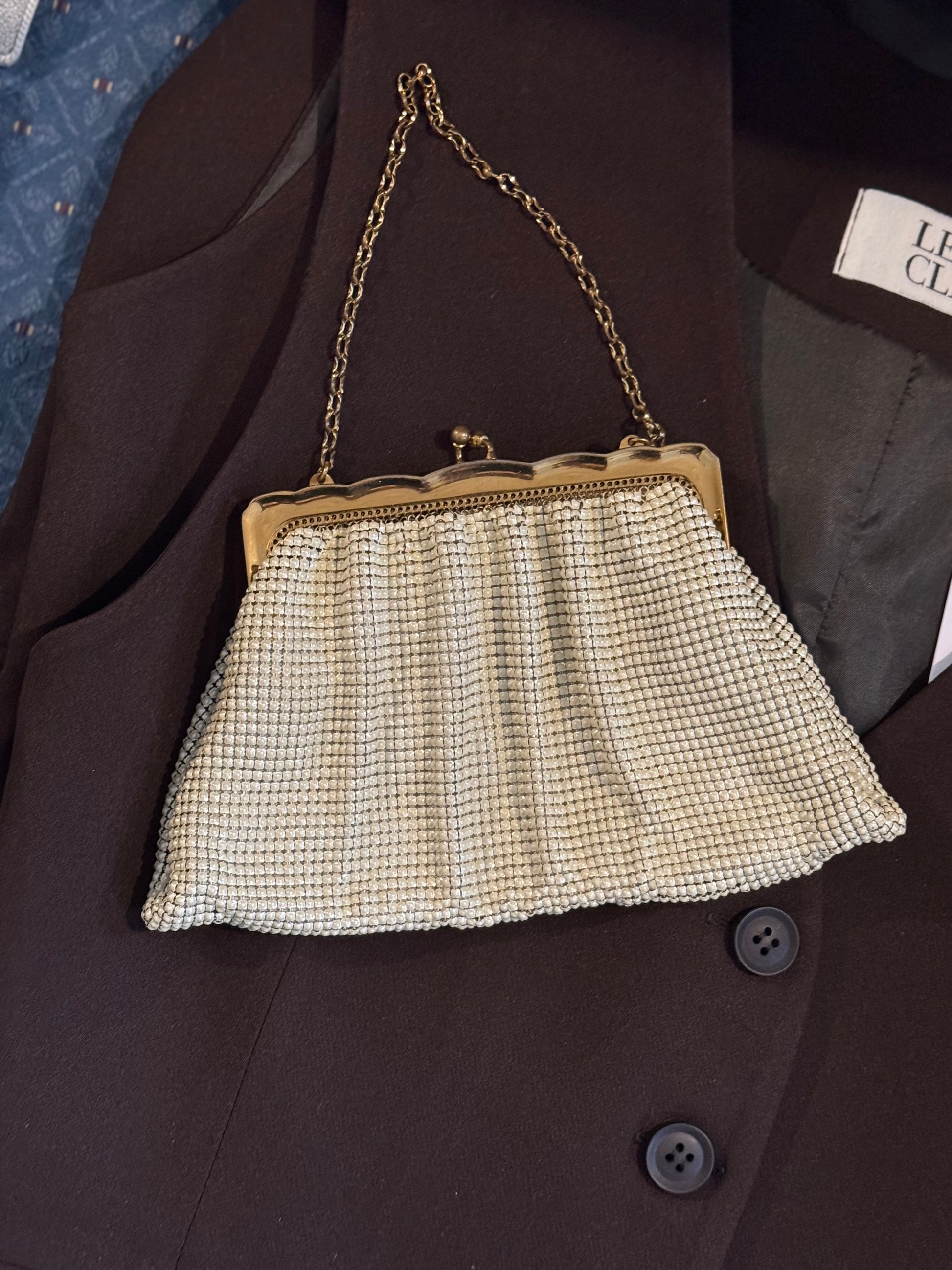 Vintage Whiting and Davis mesh change purse with ornate gold detailing lays on a chic blazer for a product shot in vintage store Petals and Jackets in Chicago.