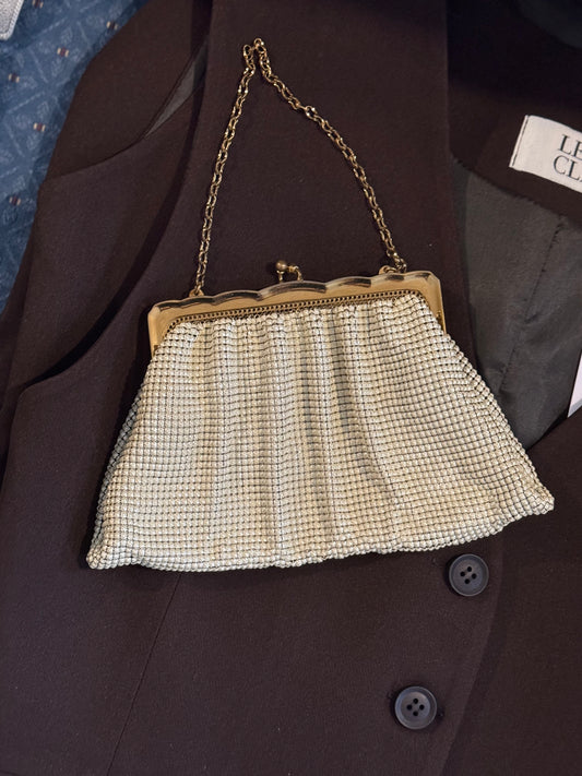 Vintage Whiting and Davis mesh change purse with ornate gold detailing lays on a chic blazer for a product shot in vintage store Petals and Jackets in Chicago.