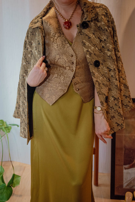 Woman layers green chic dress with gold vest with green and gold canopy chore jacket for a chic holiday styled look in Chicago.