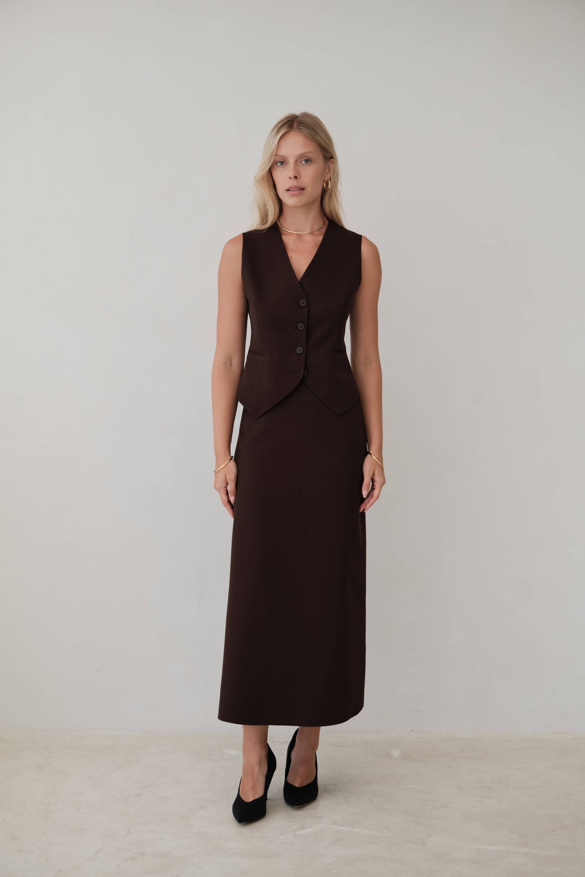 Woman wears chic brown vest overtop a matching brown skirt for a styled monotone look from Chicago boutique, Petals and Jackets.