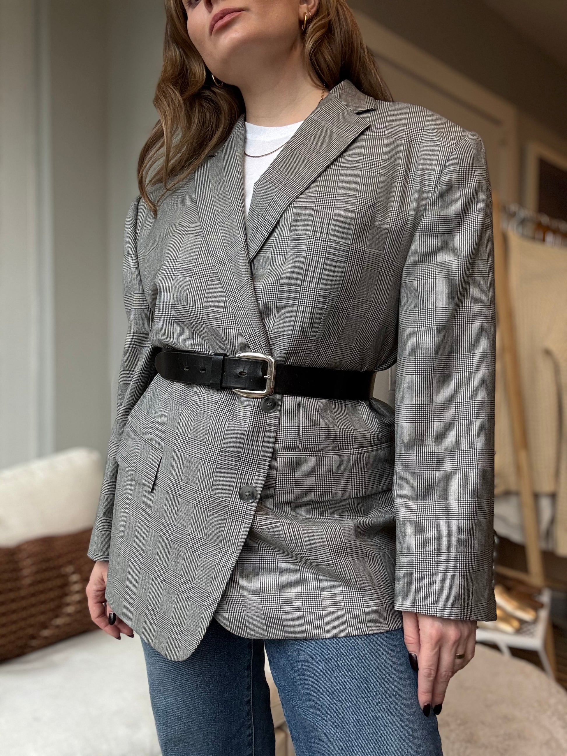 Chicago boutique owner styles oversized custom suit jacket with a black belt and jeans for a chic women's look.