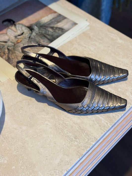 Vintage Bottega veneta metallic woven kitten heels sit on a marble table for display at local Chicago vintage shop Petals and Jackets.