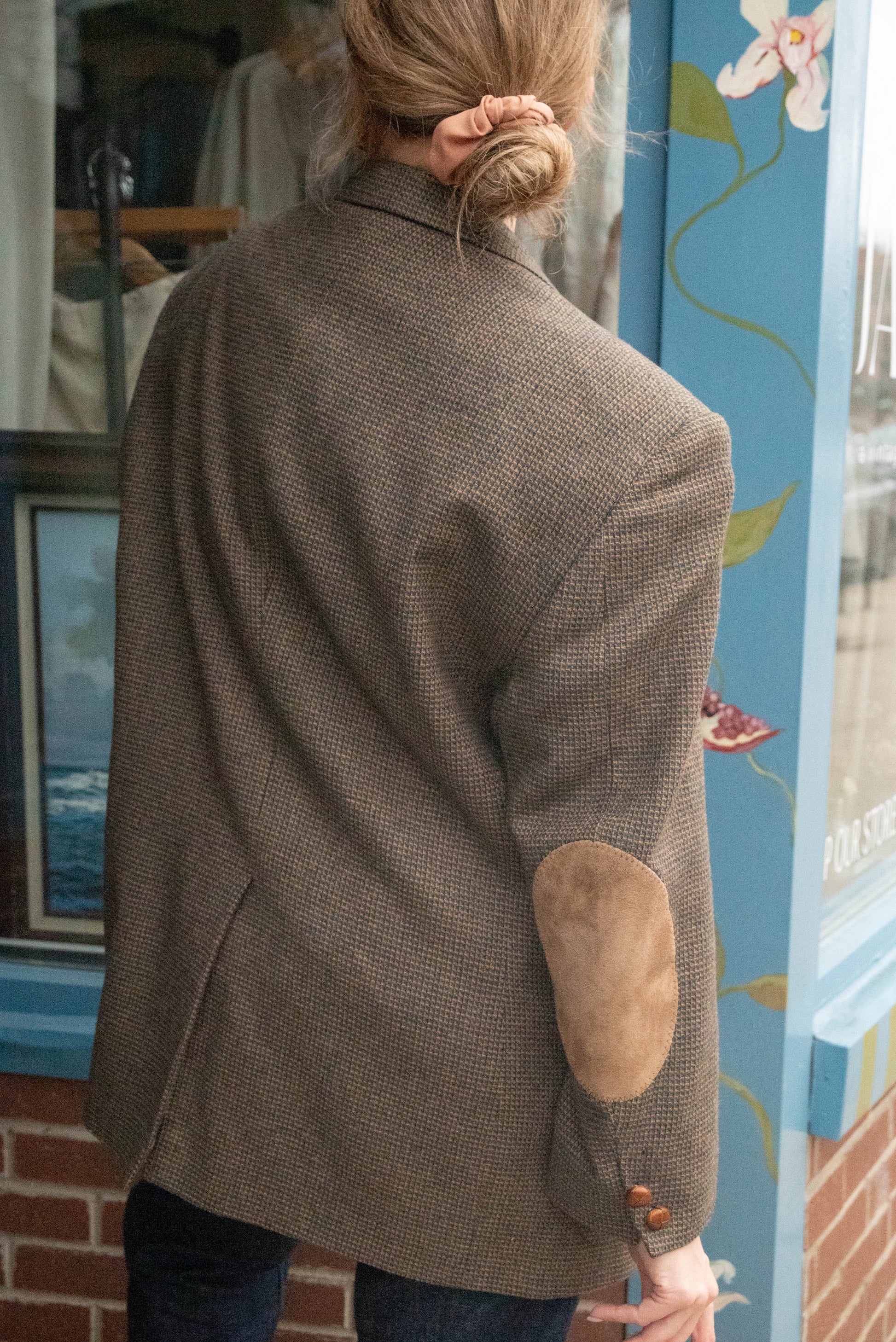 Woman poses in vintage oversized wool blazer  showing off unique suede elbow pads in front of Chicago vintage boutique Petals & Jackets.