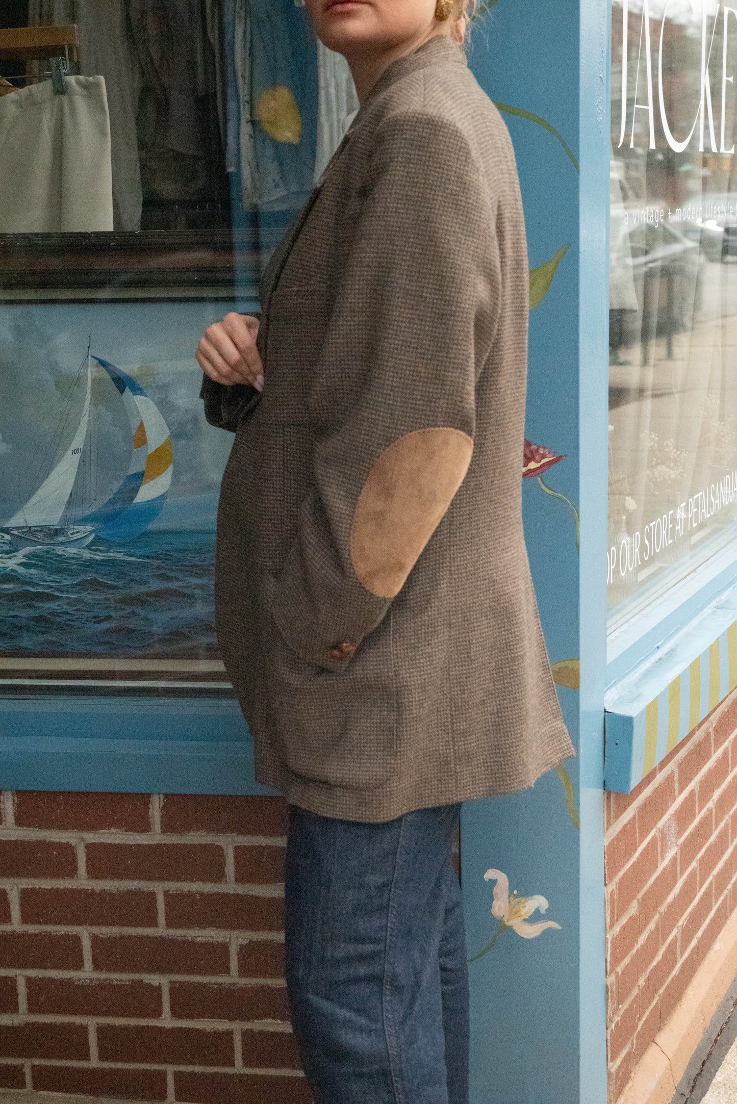 Woman poses in vintage oversized wool blazer with suede elbow pads in front of Chicago vintage boutique Petals & Jackets.