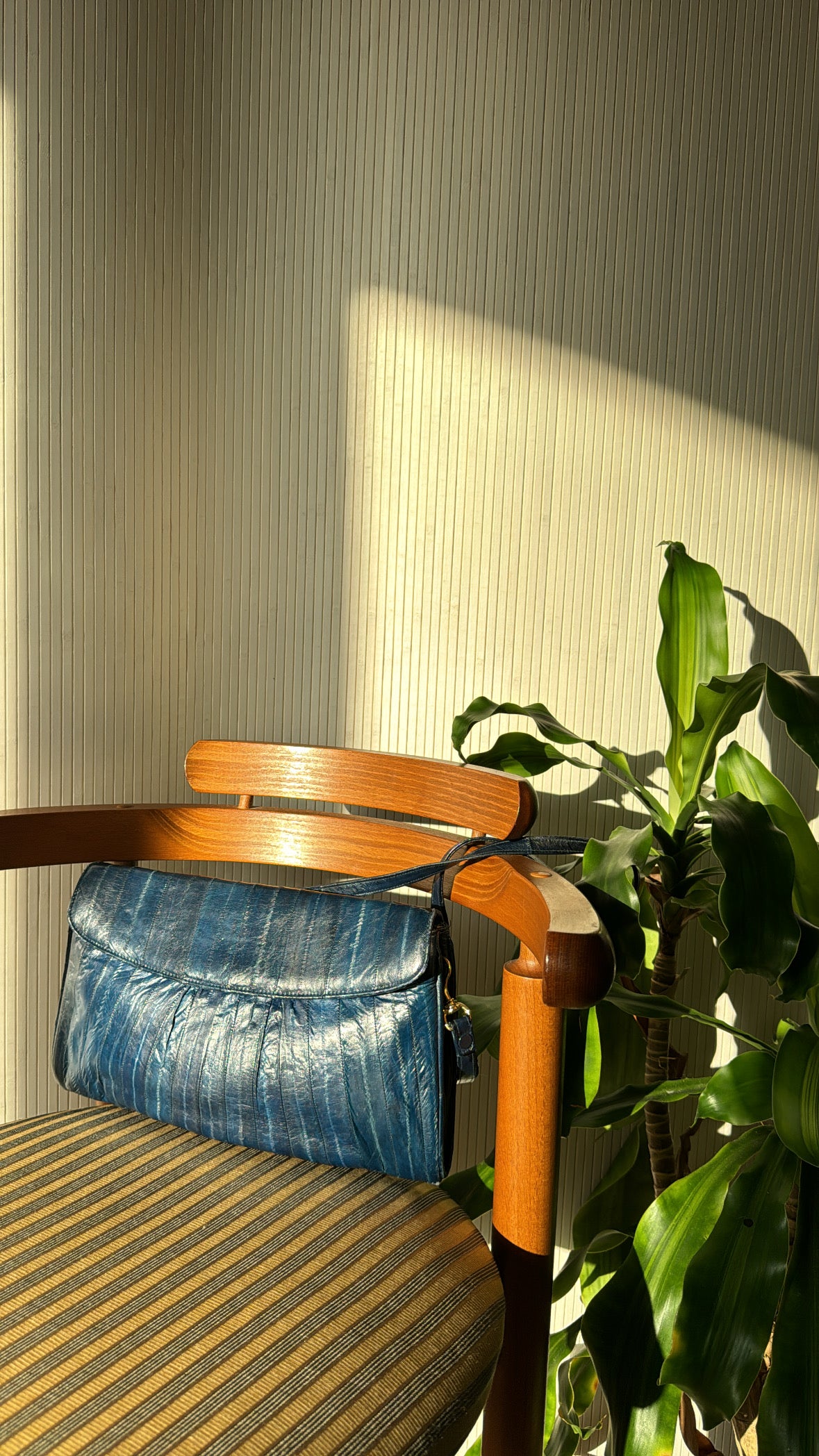 Vintage Genuine eel skin sea blue purse sits on a repurposed chair with sunlight hitting it. 