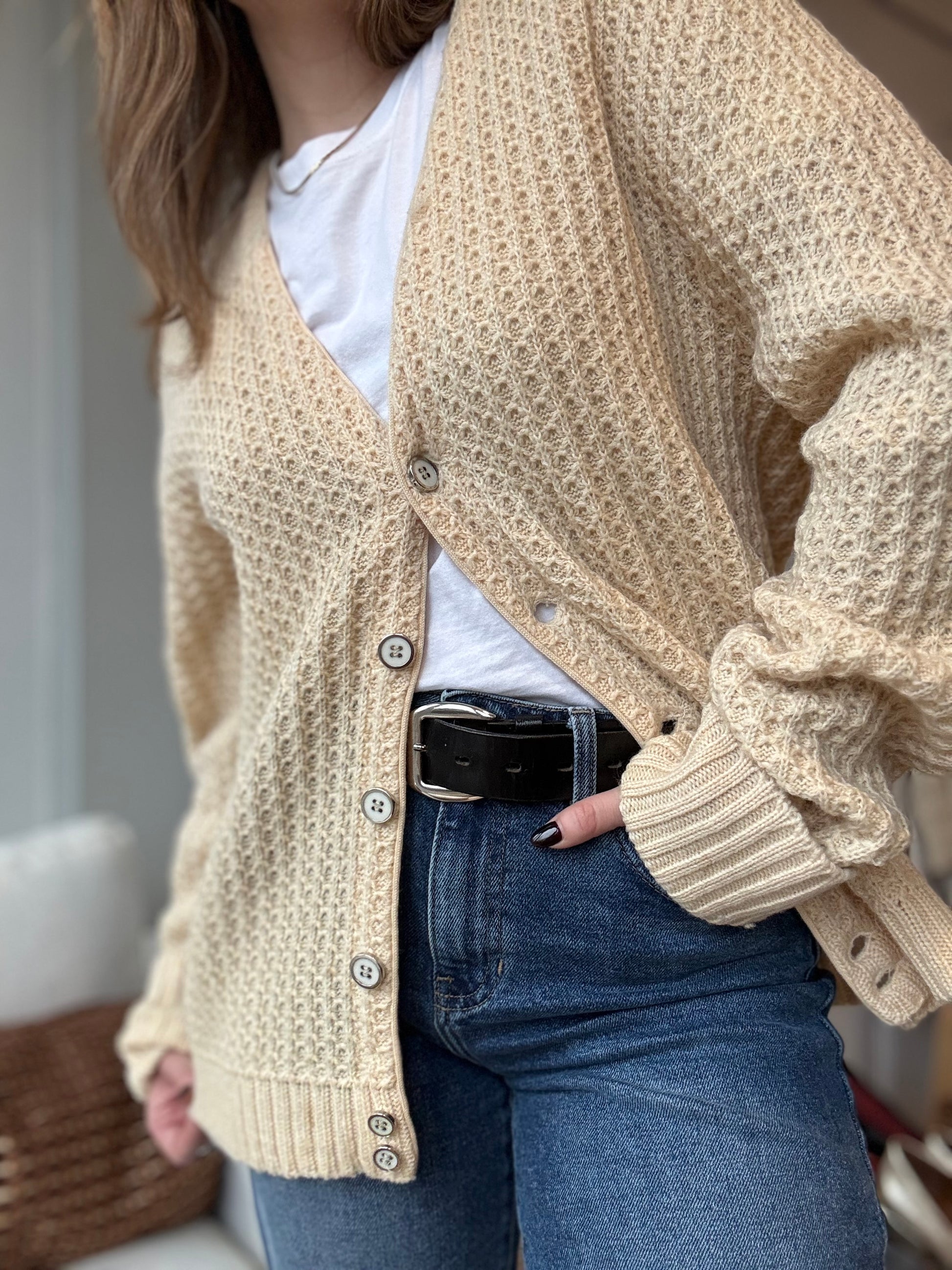 Woman poses with a vintage Jeff Ram cardigan styled with jeans and a white shirt for a chic cozy look. 
