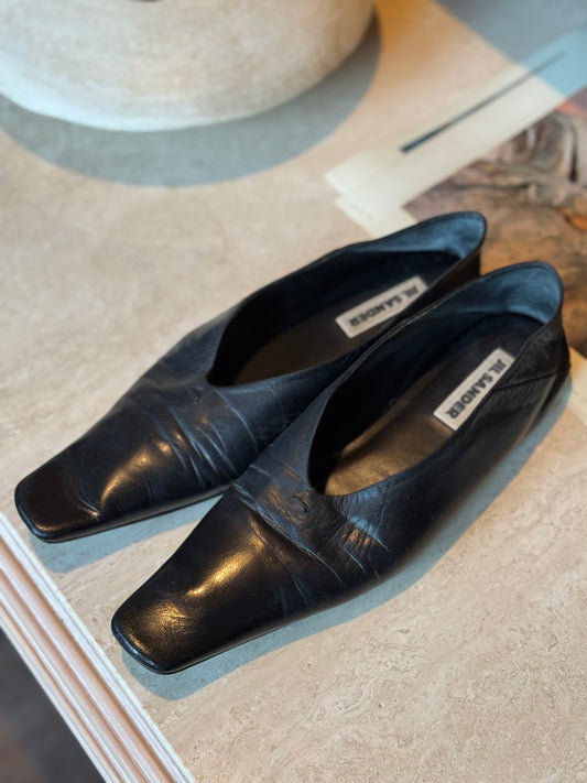 Jil Sander black flats sit on a marble table in Chicago vintage boutique in West Town.