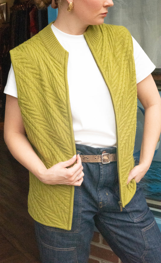 Woman stands in front of Petals and Jackets Vintage Shop in West Town Chicago Illinois wearing a vintage green vest from Coldwater Creek, denim oversized pants and a white shirt for her online vintage drops. 