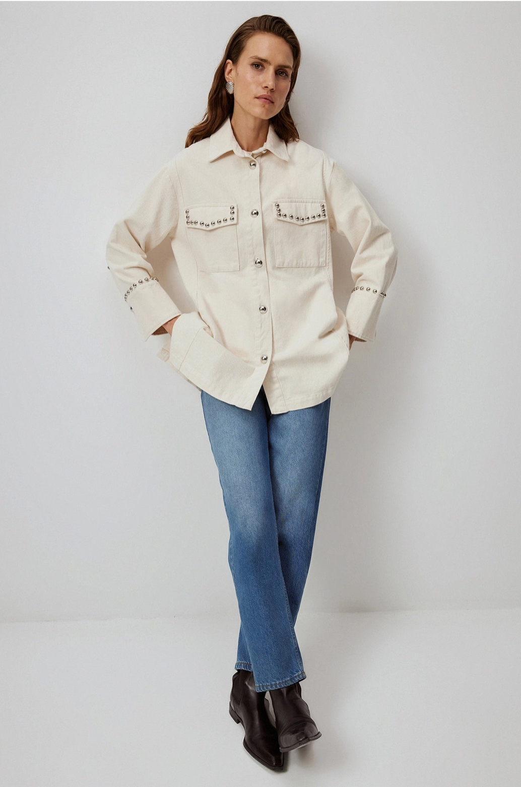 Woman wears buttoned-up western style slouchy shirt with stud accents from local Chicago sustainable boutique Petals and Jackets. 