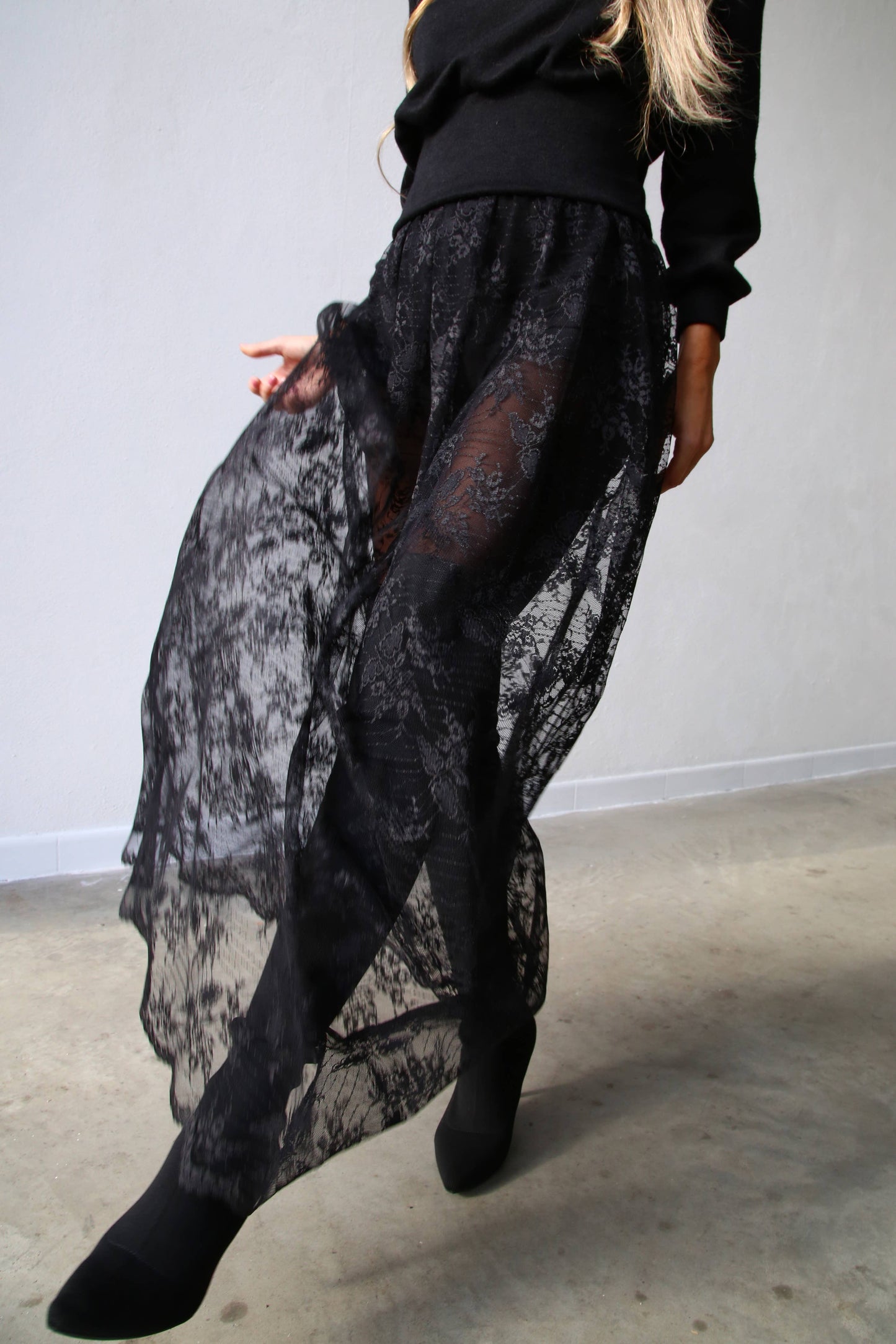 Woman wears a sheer lace skirt, styled with black tights and a black sweater for a statement styled outfit from Chicago Vintage Boutique, Petals and Jackets. 