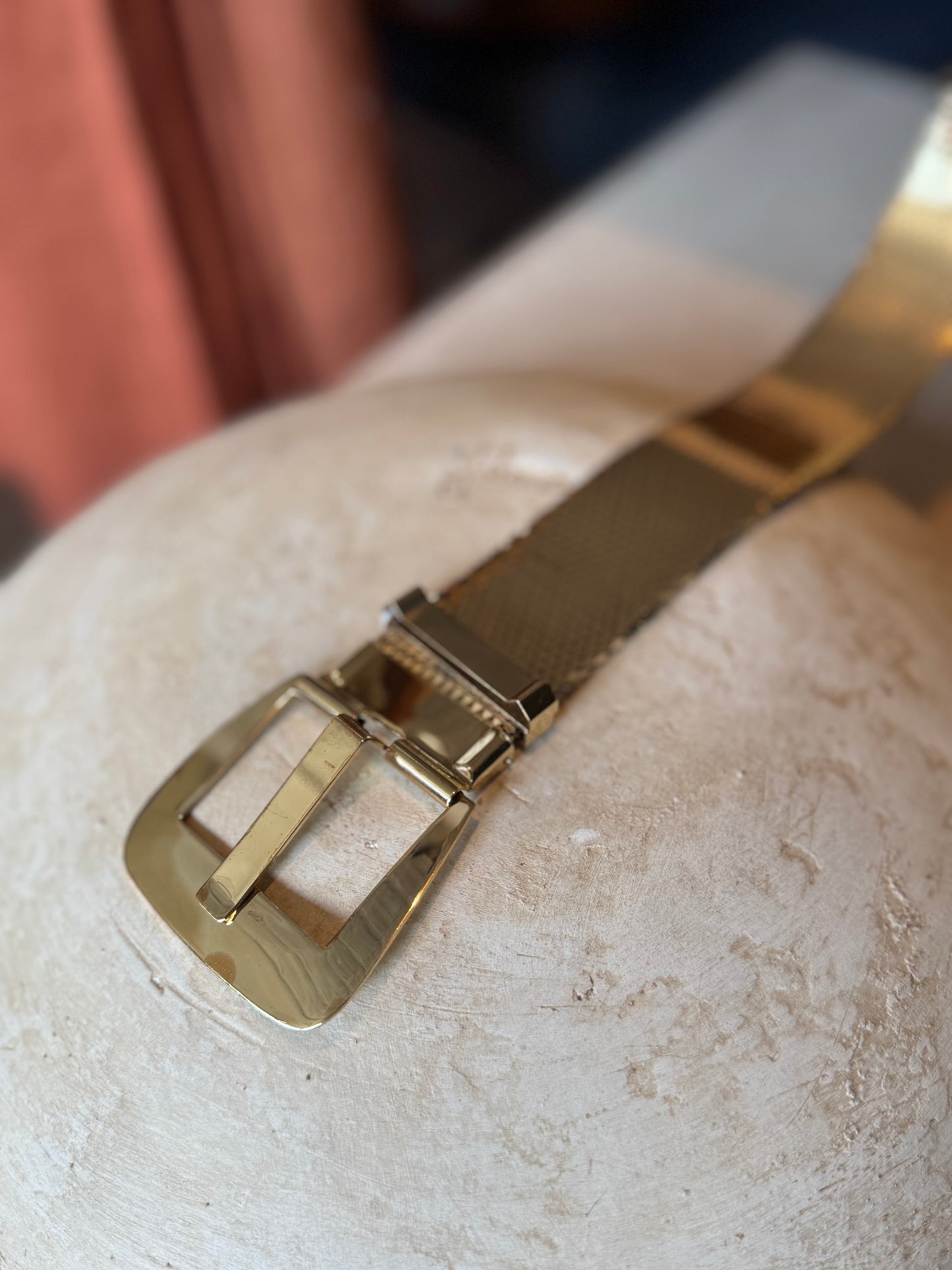 Metallic Gold vintage Whiting and Davis Belt sits on a table for a product shot in a sunny Chicago Vintage Boutique Petals  Jackets. 
