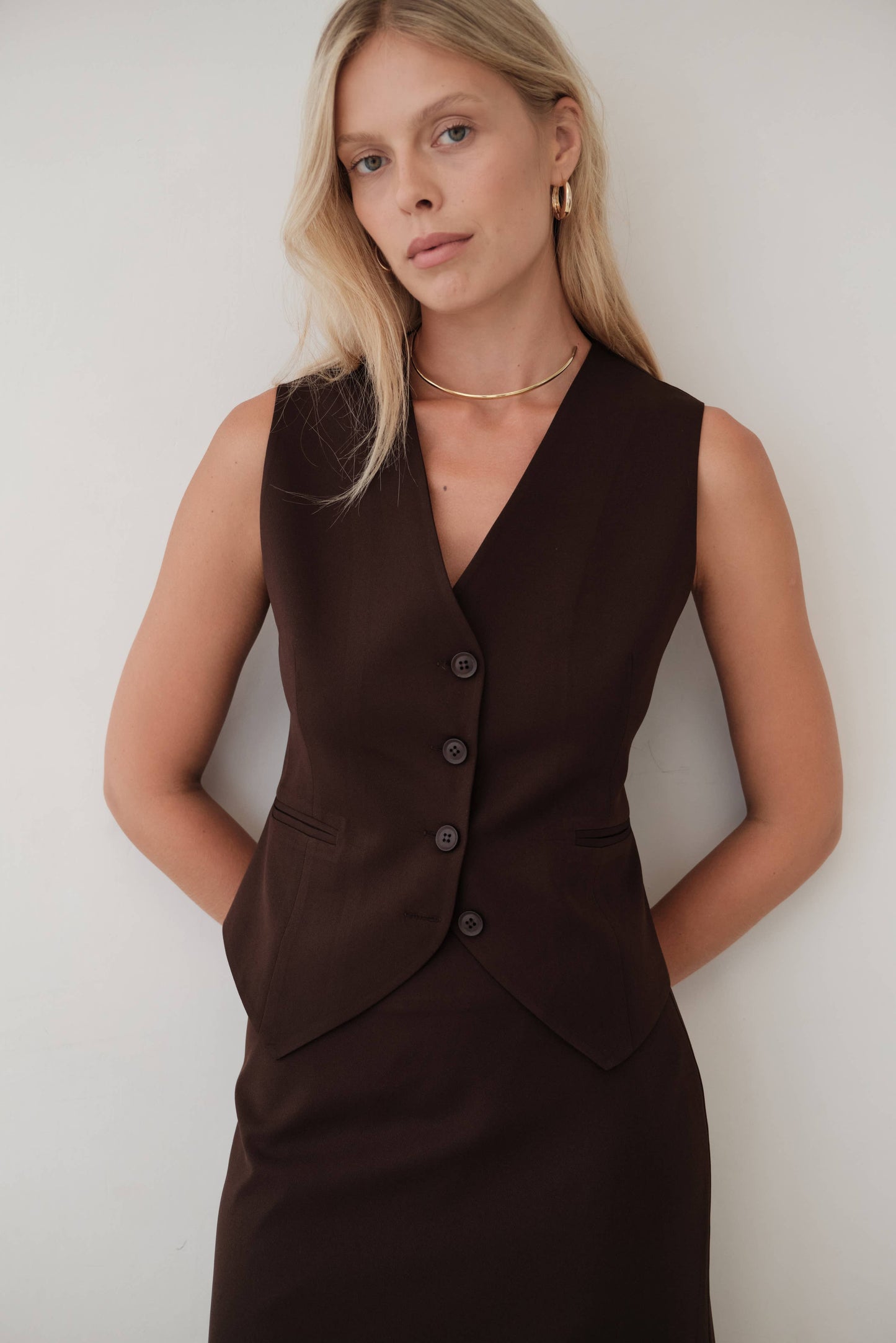 Blonde woman poses in brown vest styled with gold jewelry for a chic Italian style look from Chicago vintage and modern boutique in West Town.