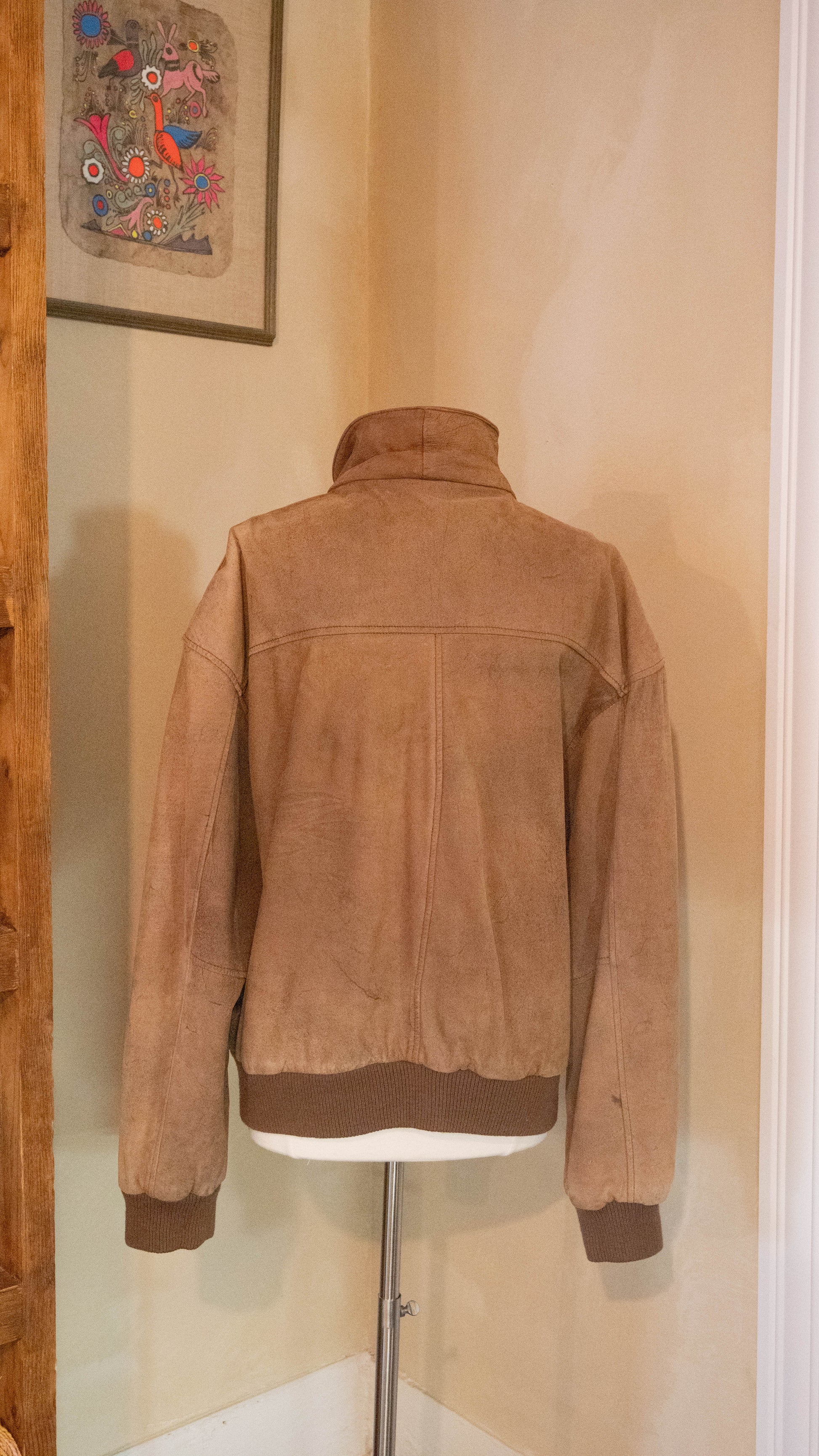 Vintage brown jacket on back of mannequin pictured in the corner of Petals and Jackets Boutique. 