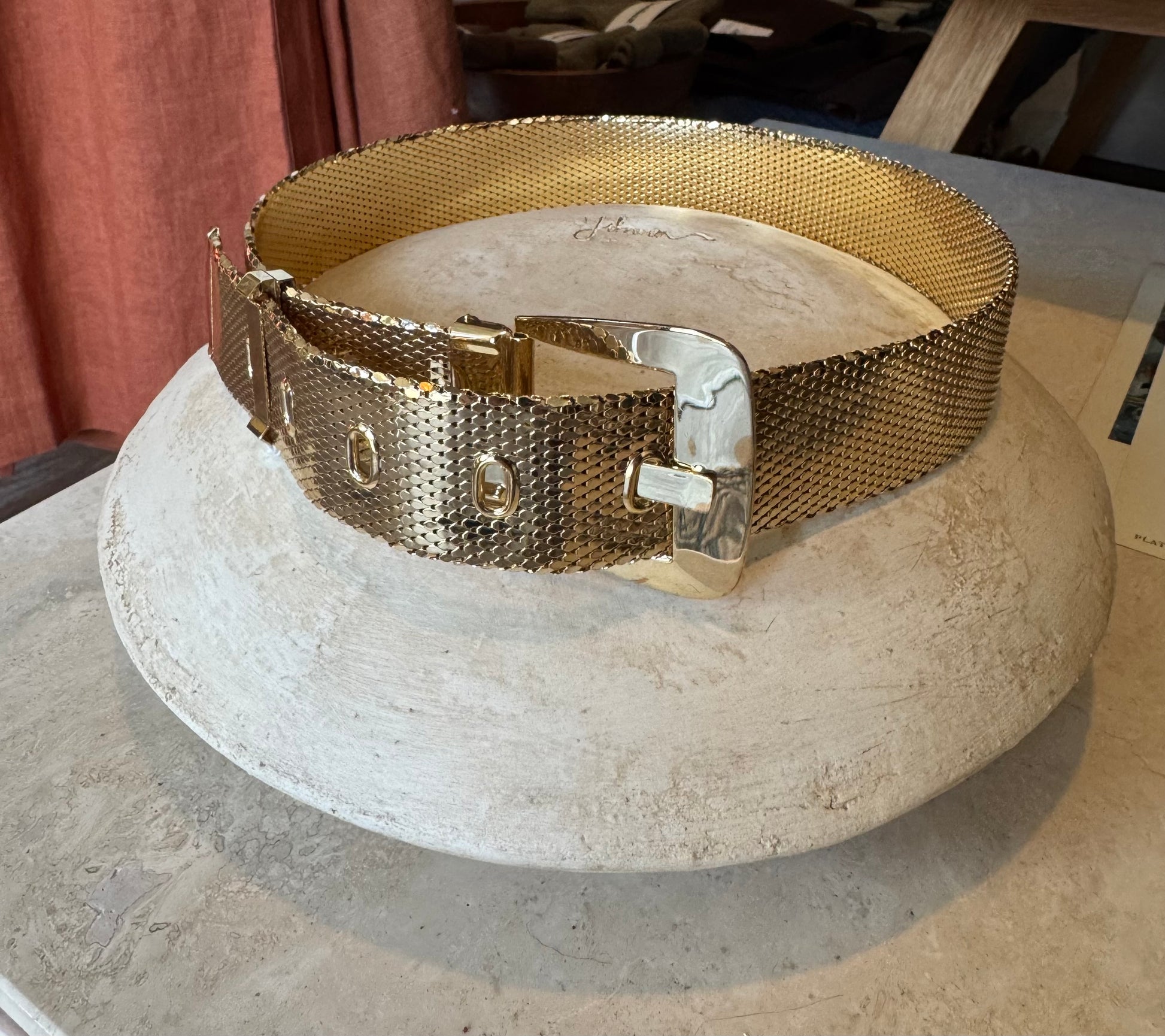 Whiting and Davis gold statement belt sits on a cream pottery block for a product shot with from a local Chicago vintage store in Chicago. 
