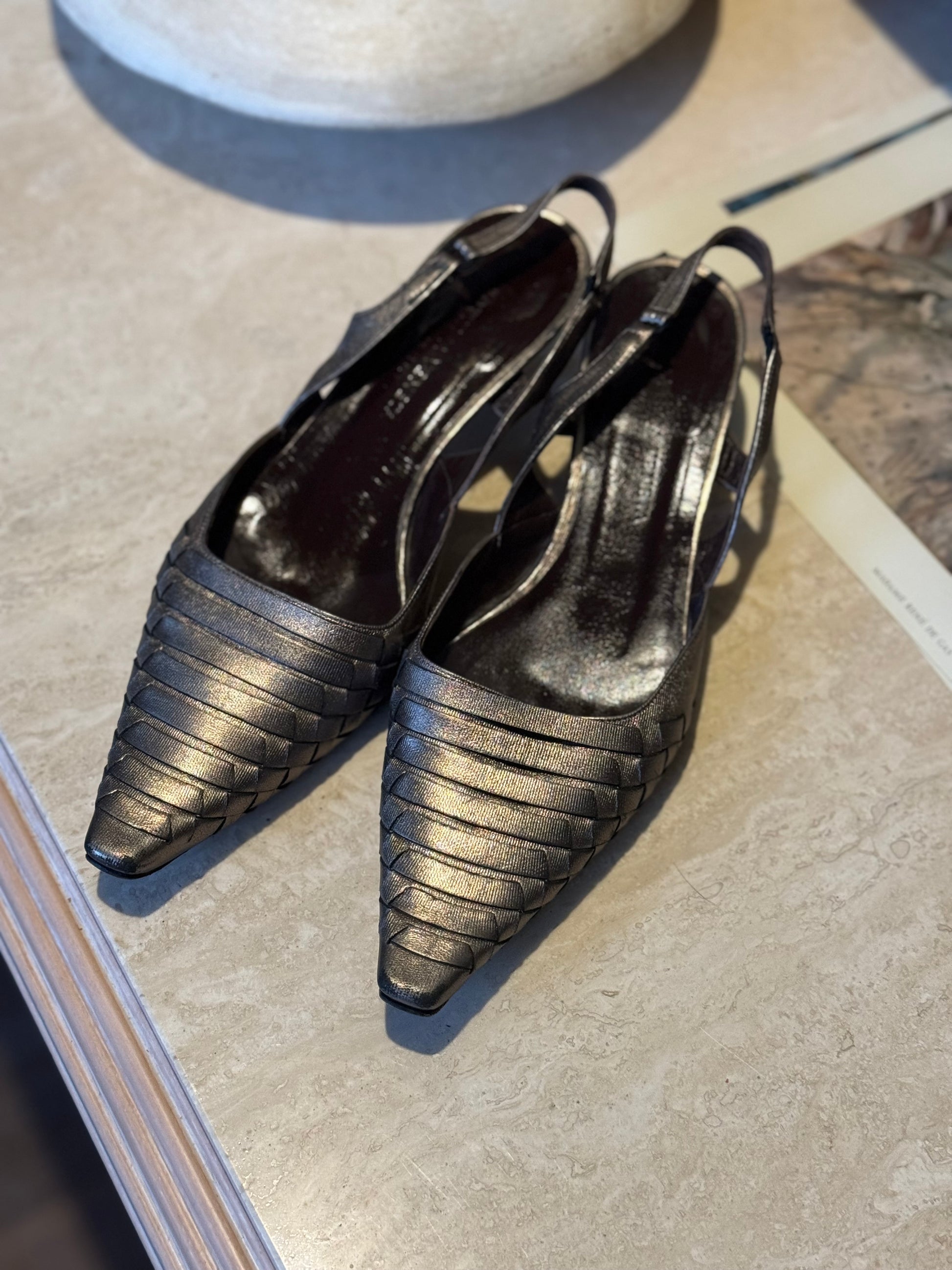 Preloved Bottega Veneta Metallic Kitten Heels sit on a marble table for a product shot in local vintage boutique Petals and Jackets in Chicago.