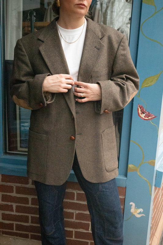 Woman poses in vintage oversized wool blazer in front of Chicago vintage boutique Petals & Jackets. 